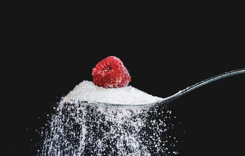 Cuillère de sucre avec une framboise au dessus